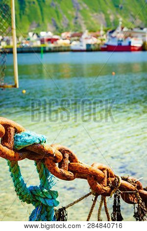 Rusty Old Metal Chain Links In Port. Marine Details. Bleik Village In The Background.