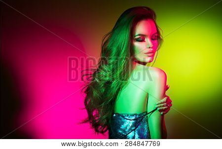 High Fashion model woman in colorful bright neon lights posing in studio, night club. Portrait of beautiful sexy seductive dancer girl in UV. Art design colorful make up. On colourful vivid background