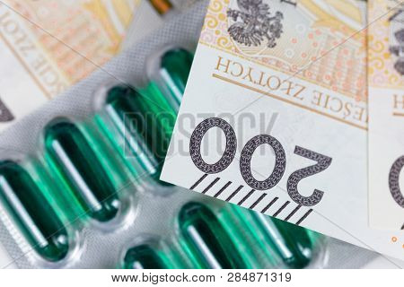 Polish currency zloty banktotes over medicine pills representing rising health care costs