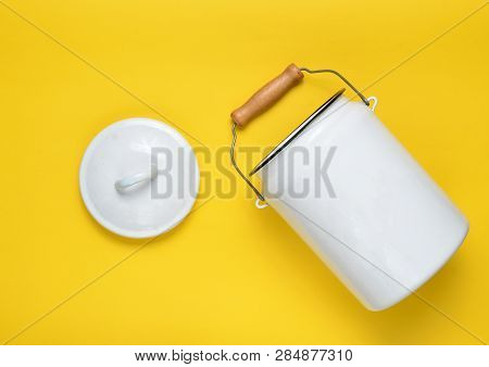 Enameled Milk Can On Yellow Pastel Background. Top View