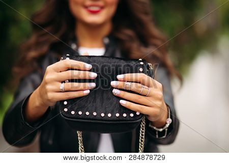 Girl With Manicured Nails With Beautiful Ornament In Wedding Rings Holding Black Fur Bag.