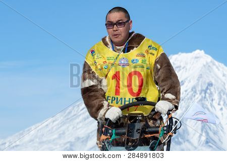 KAMCHATKA, RUSSIA - FEB 25, 2017: Portrait of running musher Nivani Ivan on background blue sky in winter sunny day. Kamchatka Sled Dog Race Beringiya, Russian Cup of Dog Sled Racing (snow disciplines)