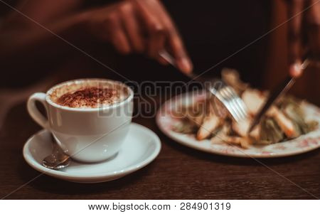 A Ceramic Cup Of Delicious Hot Chocolate Drink On The Wooden Table Of A Dark Cafe Room With Black Fe