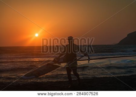 Windsurfer With His Surf Getting Out Of Water On Prasonisi Beach, Sunset (rhodes, Greece)