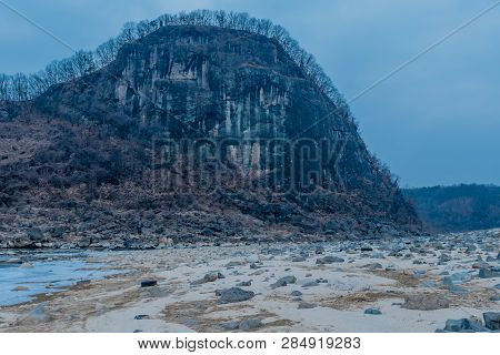 Volcanic Rocks On Sandy Beach In Front Of Jwasangbowi Rock, A Large Volcanic Rock In  Jangtan-ri, So