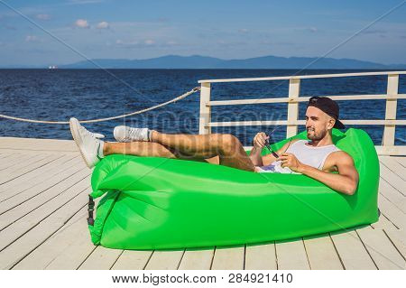 Young Man Enjoying Leisure, Lying On The Air Sofa Lamzac, Near The Sea