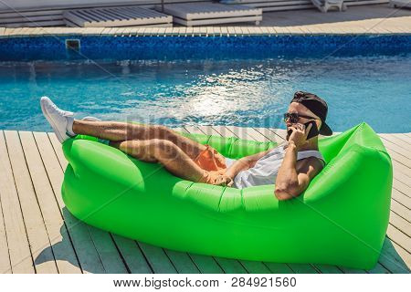 Young Man Enjoying Leisure, Lying On The Air Sofa Lamzac, Near The Pool