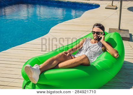Young Man Enjoying Leisure, Lying On The Air Sofa Lamzac, Near The Pool