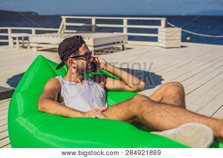 Young Man Enjoying Leisure, Lying On The Air Sofa Lamzac, Near The Sea