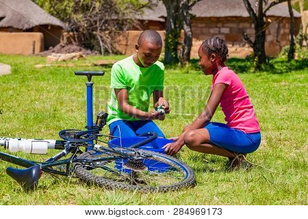 African Children Fixing A Puncture On A Bike