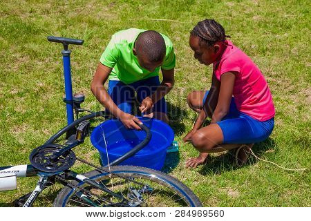 African Children Fixing A Puncture On A Bike