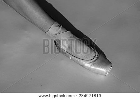 Toe Dancing. Ballerina Leg In White Ballet Shoe. Lacing Ballet Slipper. Female Foott In Pointe Shoe.
