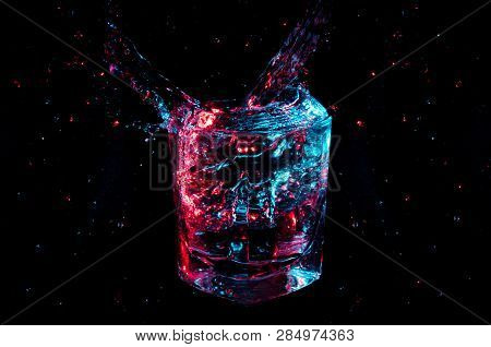 Artistic Glowing Colorful Splash From A Rocks Glass With Isolated Droplets On A Black Background