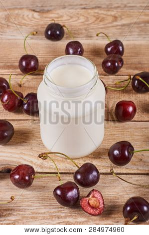 Greek Yoghurt, Opened Cherry With A Ossicle, On A Cherryes And Brown Wooden Background