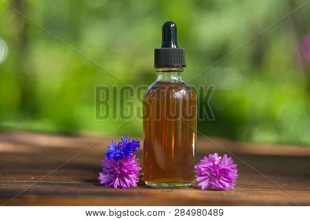Essence Of Lavender Flowers On Table In Beautiful Glass Bottle
