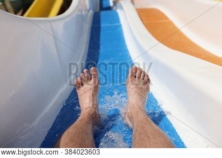 Male Feet On Background Of Roller Coaster In The Water Park Closeup. Safety Rules For Water Attracti