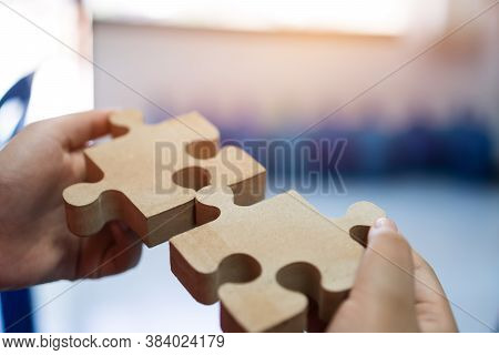 Woman Trying Connect Wooden Jigsaw Puzzle Piece. Concept Of Business Strategy In Teamwork For Soluti