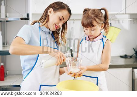 Girl Holding Measuring Jar When Her Mother Pouring Fresh Cold Milk In It
