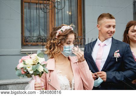 The Bride In A Medical Mask With The Groom Near The Registry Office. Wedding During The Covid-19 Epi