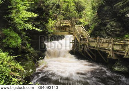 The Wooden Boardwalk Within The Bushkill Falls Scenic Area In Pennsylvania In Early Springtime.