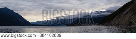 Beautiful Panoramic View Of Muncho Lake In The Canadian Northern Rockies During A Cloudy Sunrise. Ta