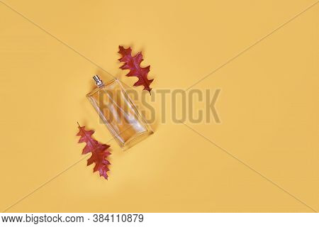 Eau De Toilette In A Transparent Bottle And Autumn Red Leaves Oak Lies Beautifully On A Yellow Backg