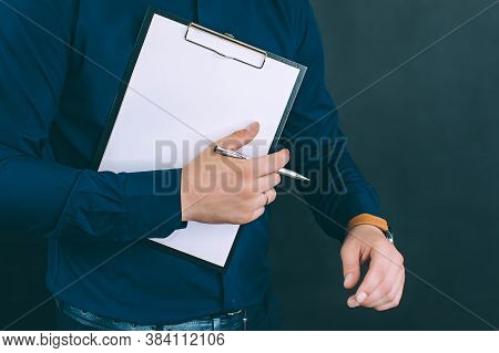 Businessman With A Folder For Documents And A Watch In His Hands, On A Black Background.