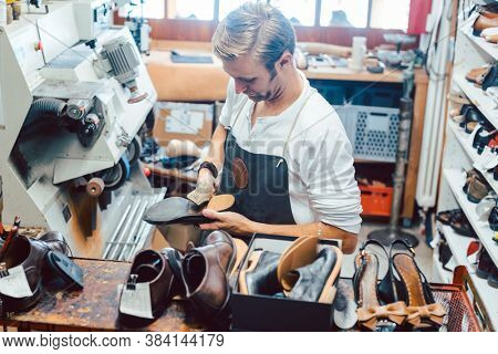 Shoemaker with shoes to repair on a rack in his workshop seen from above