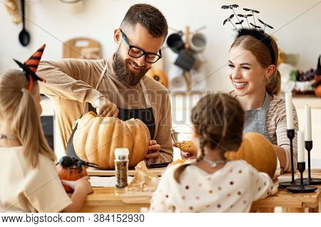 Cheerful Bearded Man Making Jack O Lantern From Pumpkin While Gathering Around Table With Woman And 