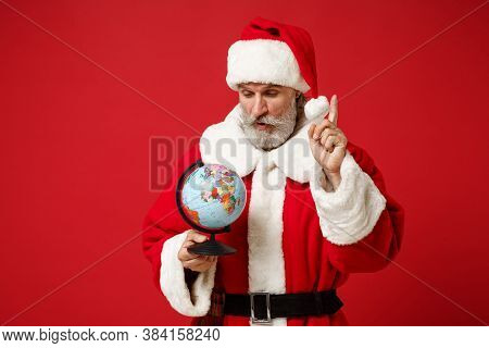 Pensive Elderly Gray-haired Mustache Bearded Santa Man In Christmas Hat Posing Isolated On Red Backg