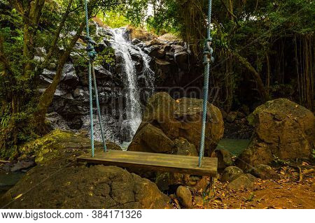 Tropical Landscape. Beautiful Hidden Waterfall In Rainforest. Blurred Swing. Selected Focus. Adventu
