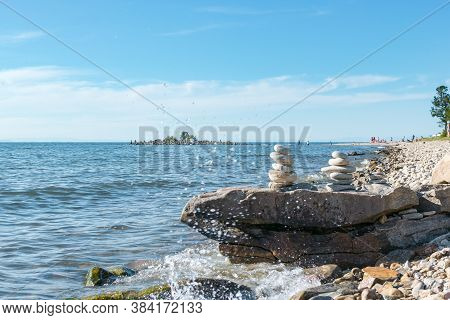 Pyramids Of Stacked Stones On A Rock On The Inshore Waves Of Lake Baikal, Scenic Seascape, Balance A
