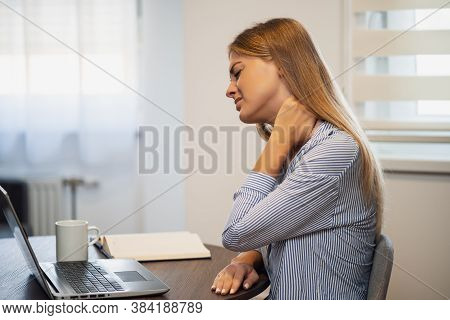 Young Modern Woman Is Working From Home. She Is Having Pain In Neck.