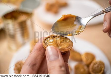 Filling The Halves Of Cookie Nuts With Boiled Condensed Milk. Women's Hands Fill Cookies With Boiled