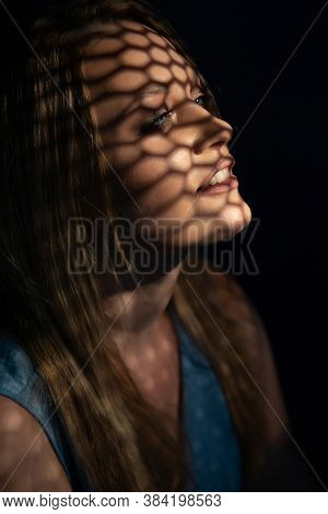 Beautiful woman confesses in the confessional. Praying woman, fine art portrait with interesting ligth and shadow pattern. Absolution. 