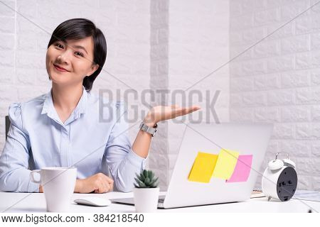 Happy Woman Sitting At Home Office And Pointing To Copy Space