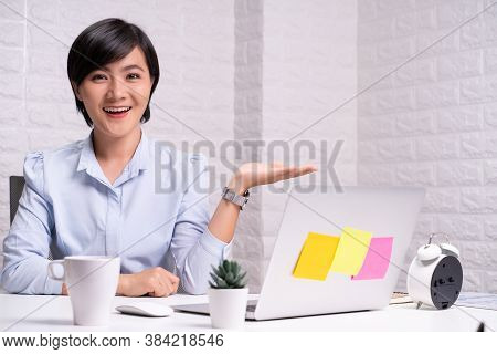 Happy Woman Sitting At Home Office And Pointing To Copy Space