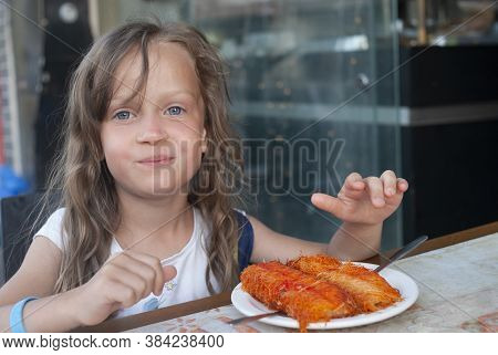 Five Years Old Beautiful European Girl With Blue Eyes  And Curly Long Hair Eating Middle East Desser