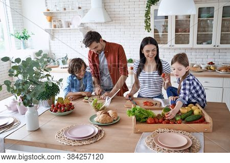 Preparing A Salad. Young Beautiful Family Cooking Together In The Modern Kitchen At Home. Mother And