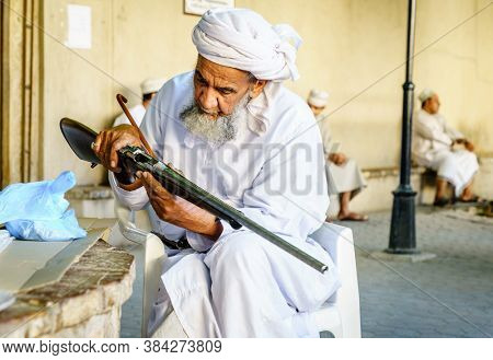 Nizwa, Oman, December 2, 2016: An elderly man is inspecting a hunting rifle at the Friday gun market in Nizwa, Omam