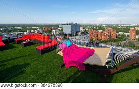 Rooftop Terrace With Green Grass. View Of City From The Top. Relaz Zone With Hammock And Couch.