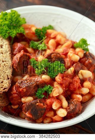 Bean And Chorizo Stew Served In White Bowl With Parsley