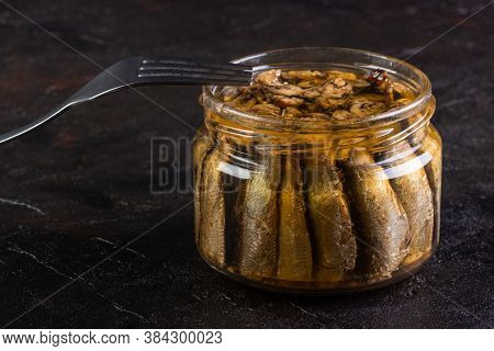 Glass Jar Of Sprots With A Fork On A Concrete Background