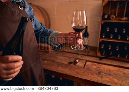 Male Sommelier Holding Bottle And Glass Of Red Wine