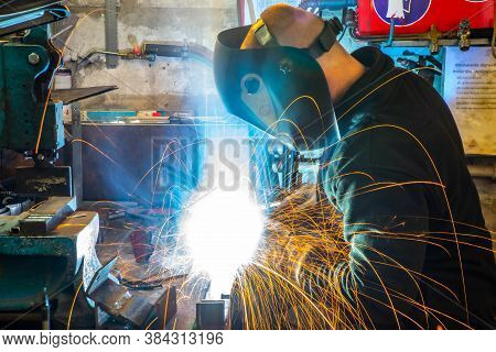 Electric Welding Process. Worker In Welding Mask. Yellow Sparks Fly To The Sides. Bright White.