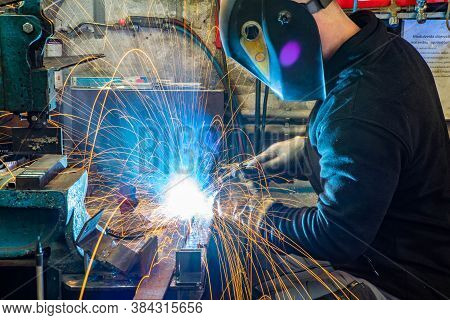 Electric Welding Process. Worker In Welding Mask. Yellow Sparks Fly To The Sides. Bright White.