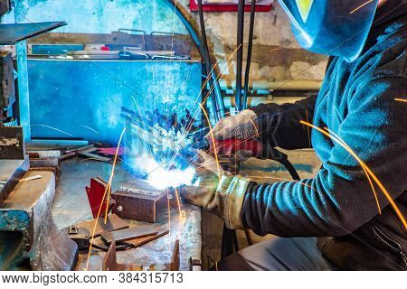 Electric Welding Process. Worker In Welding Mask. Yellow Sparks Fly To The Sides. Bright White.