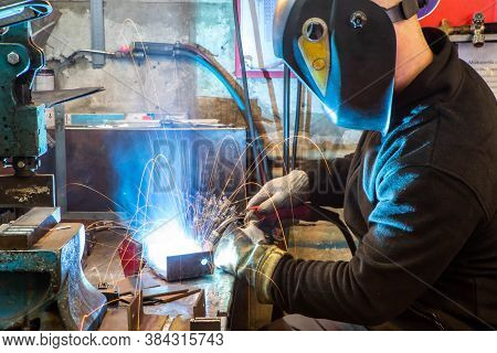 Electric Welding Process. Worker In Welding Mask. Yellow Sparks Fly To The Sides. Bright White.