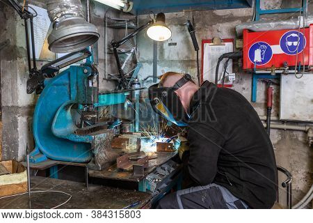 Electric Welding Process. Worker In Welding Mask. Yellow Sparks Fly To The Sides.