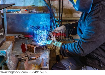 Electric Welding Process. Worker In Welding Mask. Yellow Sparks Fly To The Sides. Bright White And B